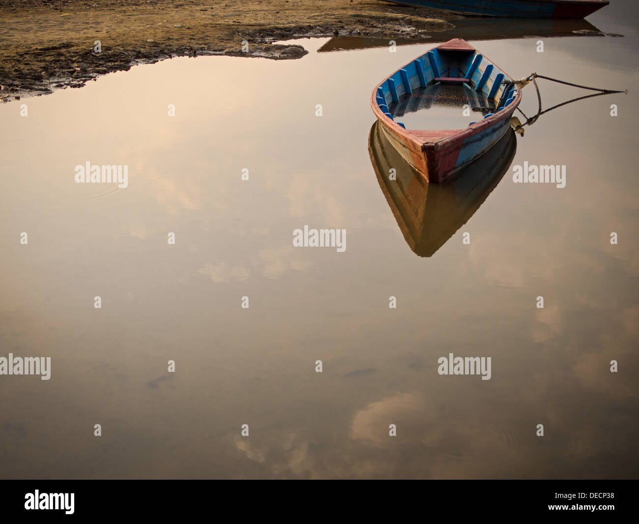 Un bateau à rames en bois marooned, ancrée, flottant sur les eaux calmes d'un lac. Banque D'Images