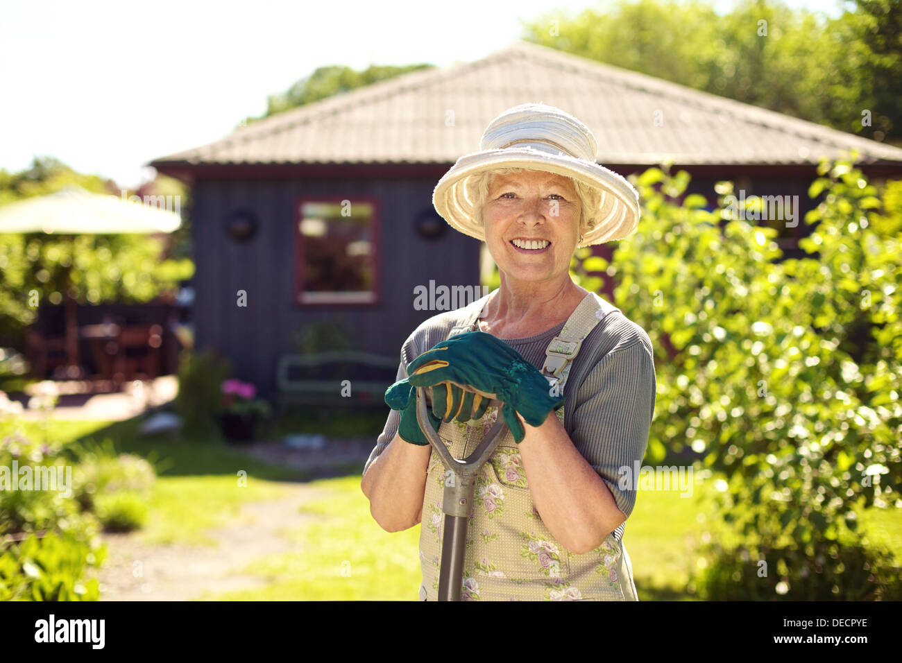 Portrait of smiling senior woman avec les outils de jardinage à l'extérieur. Plus femme debout avec une pelle dans son jardin jardin Banque D'Images