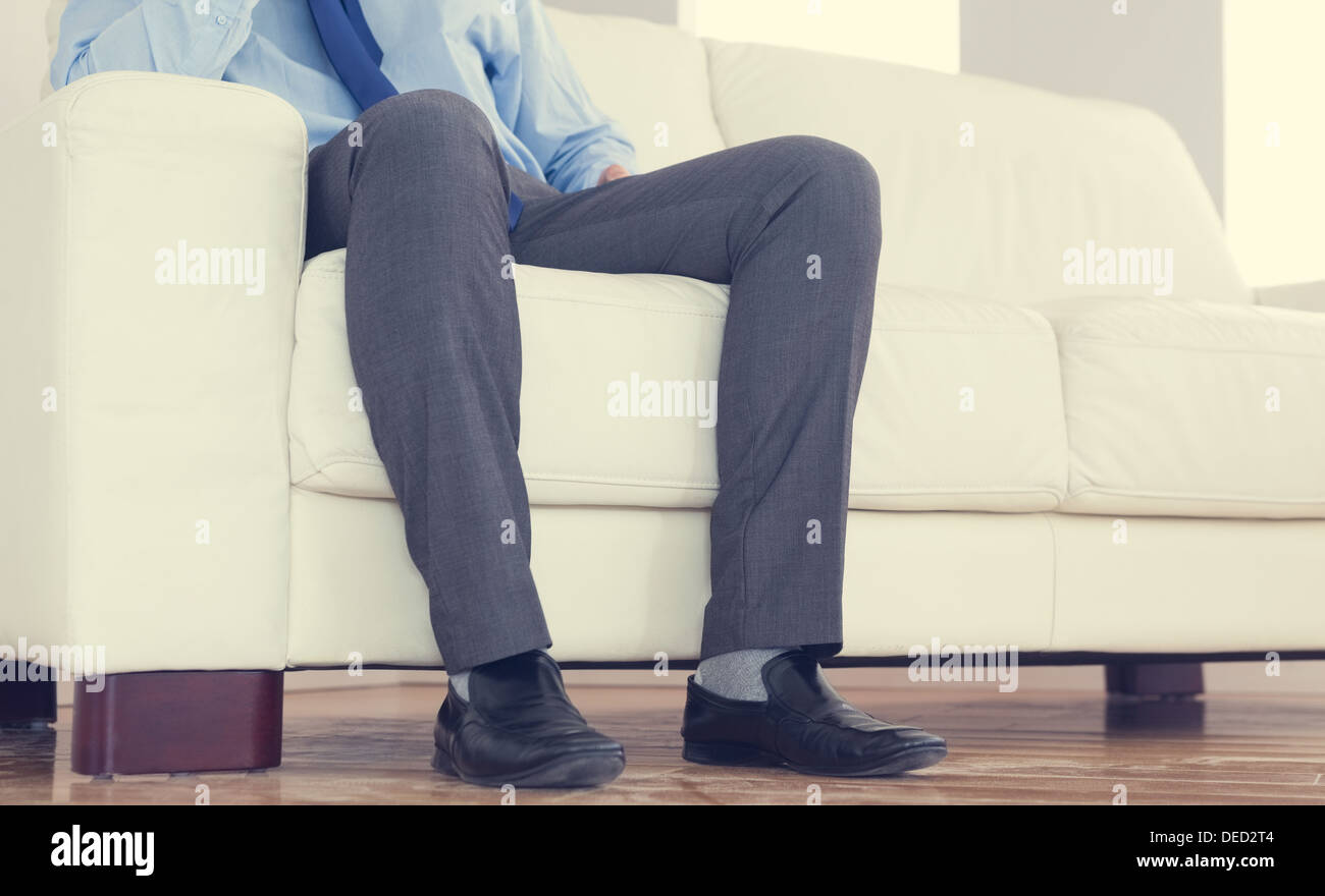 Partie basse de classy businessman sitting on cosy sofa Banque D'Images