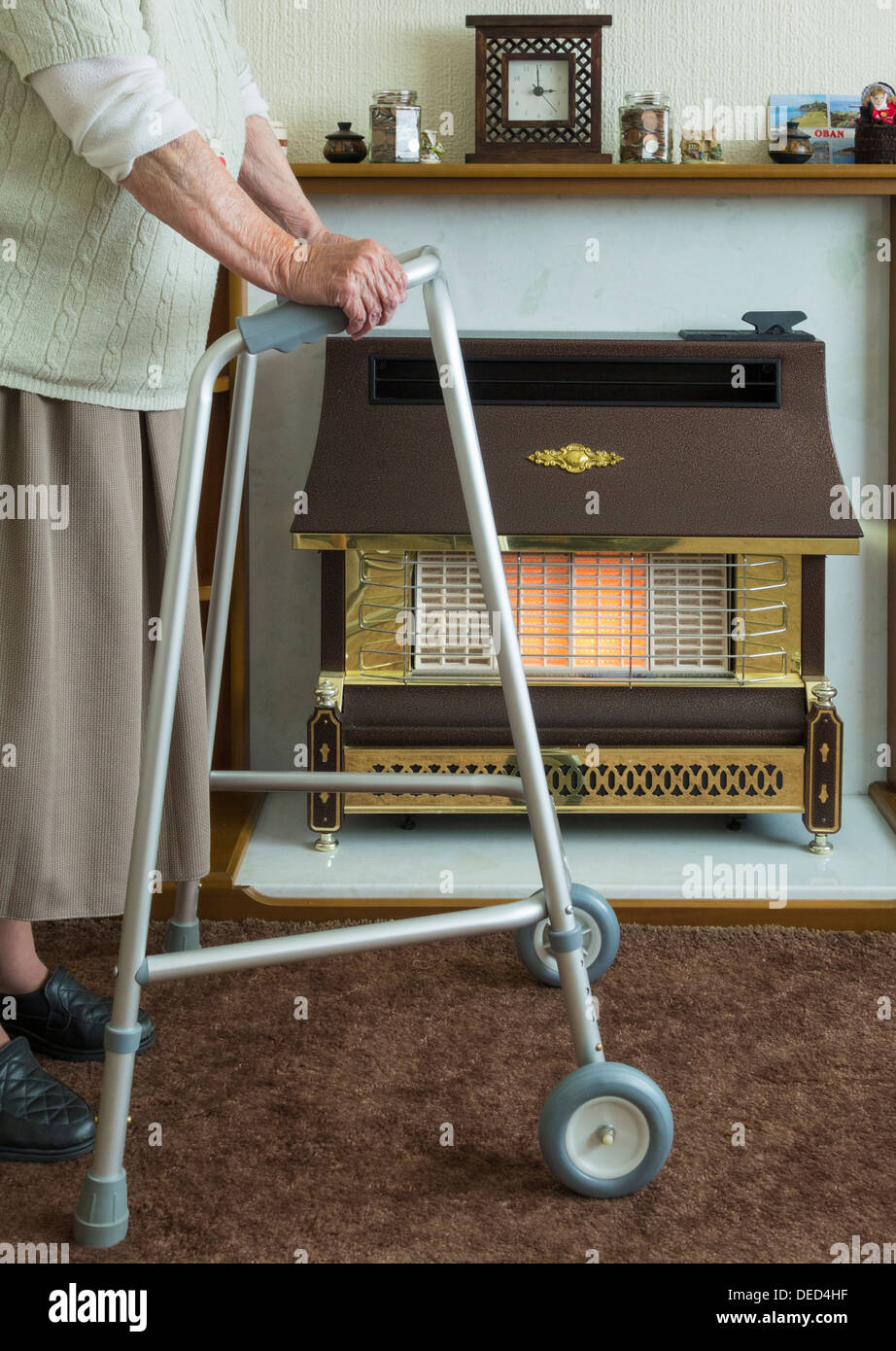 Dame âgée dans sa quatre-vingt-dix avec la marche près du feu de gaz. Banque D'Images