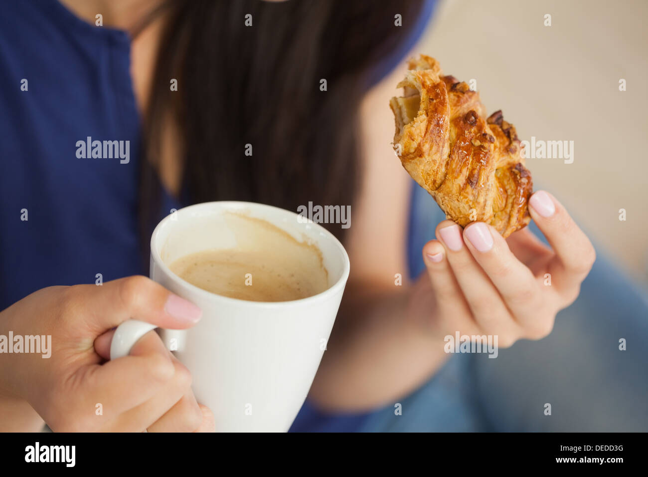 Femme ayant une pâtisserie avec une tasse de café Banque D'Images