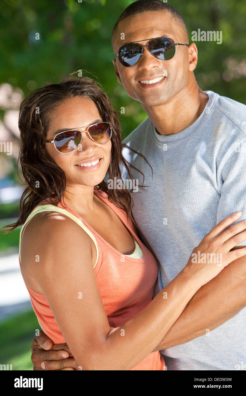 Une happy African American man and woman couple dans la trentaine portant des lunettes de soleil à l'extérieur ensemble smiling Banque D'Images