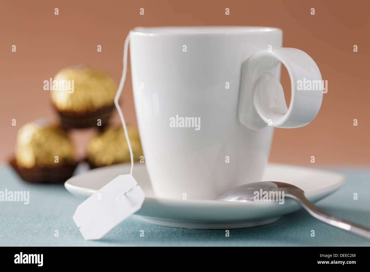 Close up of white tasse et soucoupe avec des chocolats en arrière-plan Banque D'Images