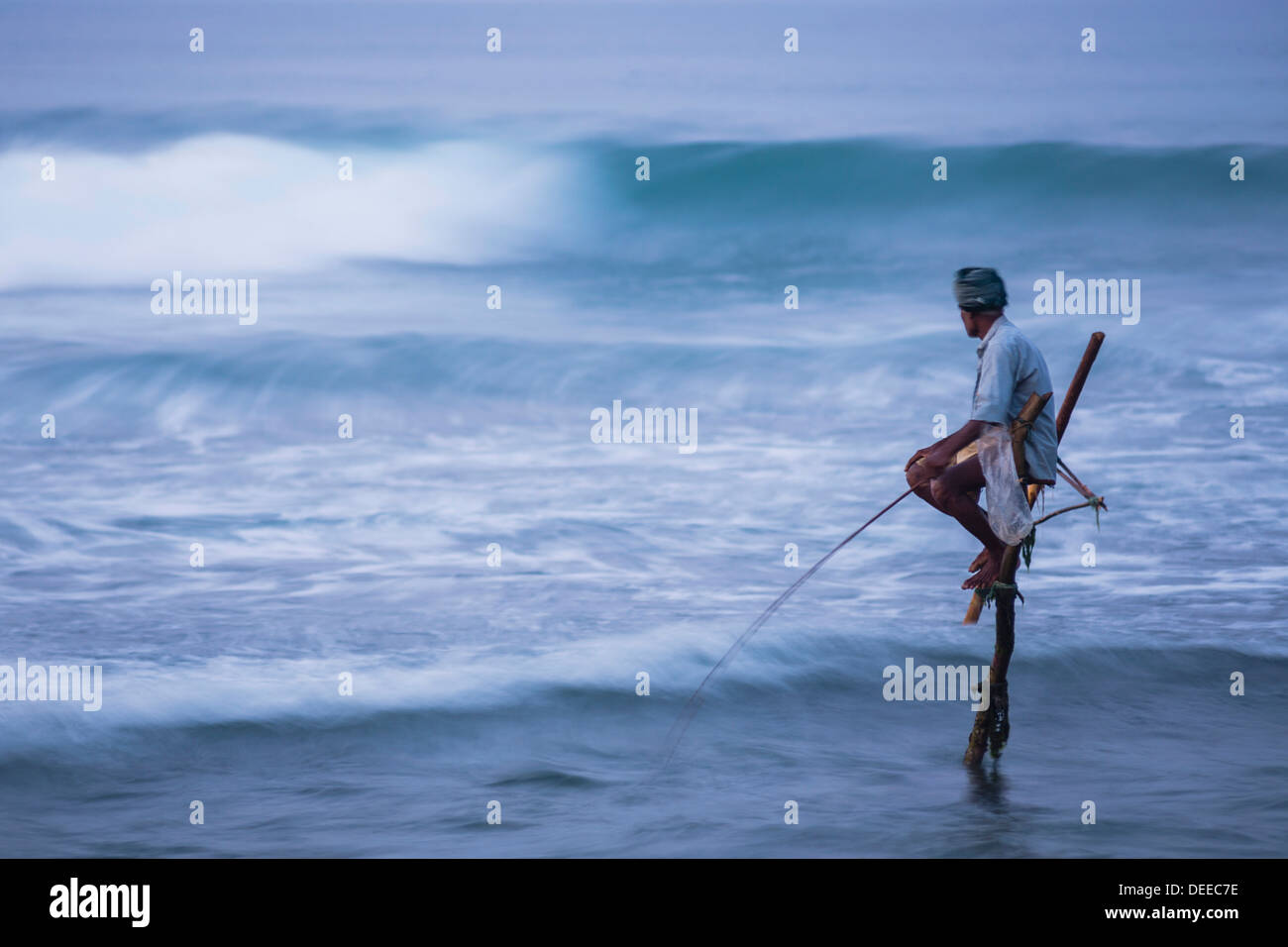 Pêche à échasses, un pêcheur sur pilotis dans les vagues à Midigama près de Weligama, Côte Sud, Sri Lanka, de l'Océan Indien, l'Asie Banque D'Images