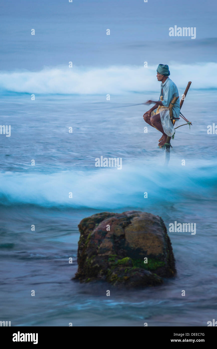 Pêche à échasses, un pêcheur sur pilotis dans les vagues à Midigama près de Weligama, Côte Sud, Sri Lanka, de l'Océan Indien, l'Asie Banque D'Images