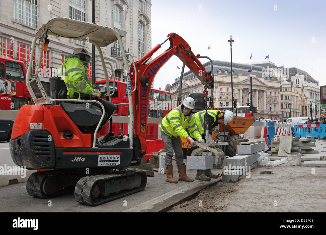 Ouvriers utiliser un mini-excavatrice pour placer des pierres comme bordure pavés sont remplacés et prolongé à Londres Piccadilly Banque D'Images