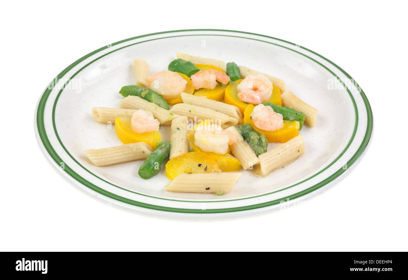 Une plaque avec une assiette de crevettes cuites avec les courgettes, les asperges et les pâtes sur un fond blanc. Banque D'Images