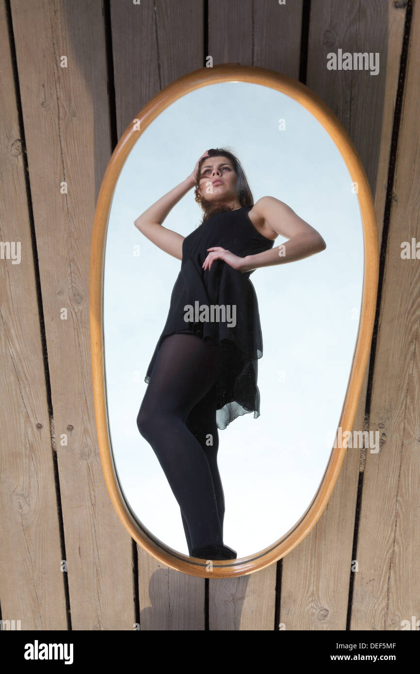 Young Woman in Black avec son reflet dans le miroir - concept solitaire solitude Banque D'Images