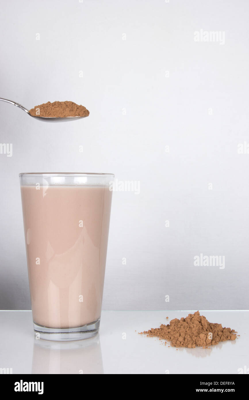 Verre de lait au chocolat avec poudre et cuillère Banque D'Images