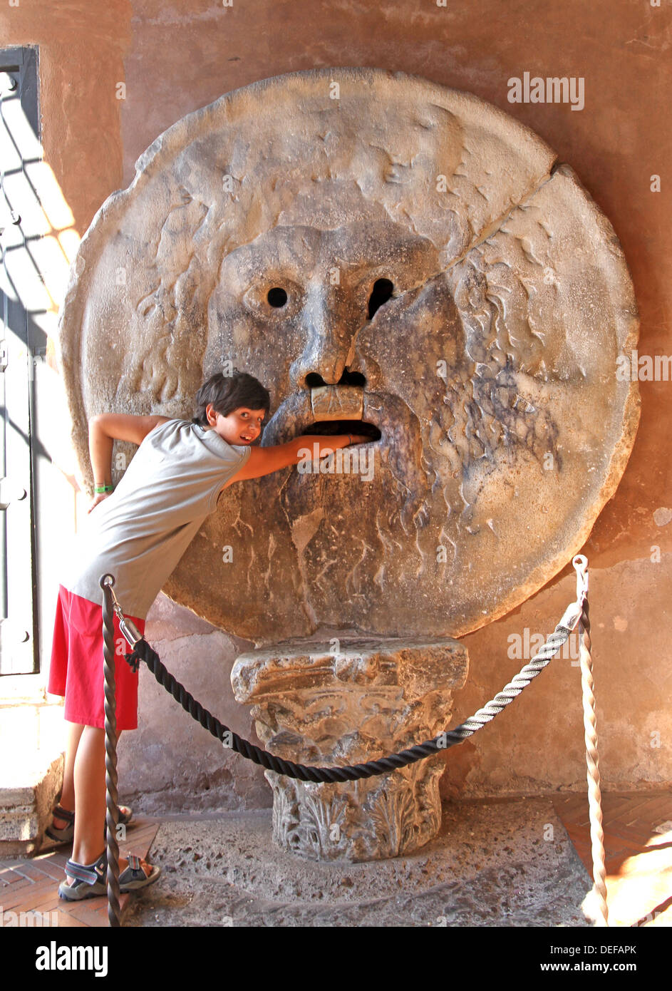 Jeune adolescent met sa main à l'intérieur de la Bocca della Verità, Rome Banque D'Images