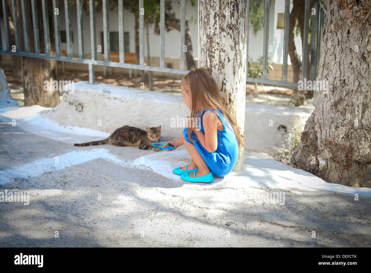 Peu cute girl jouer avec un chat dans les rues d'Emporio, Santorini, Grèce Banque D'Images