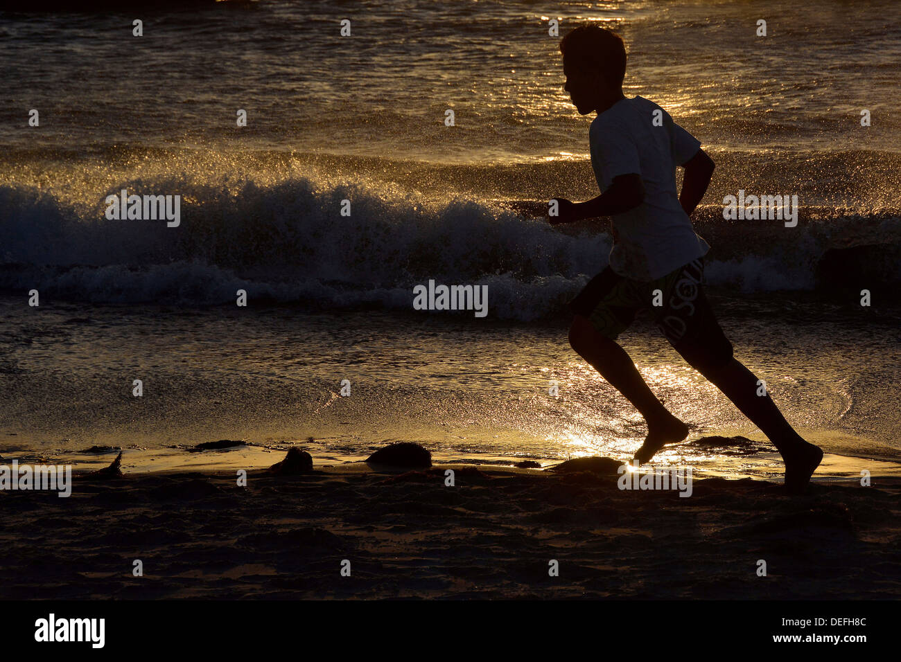 Man jogging le long d'une plage, silhouette au coucher du soleil, Jericoacoara, Ceará, Brésil Banque D'Images