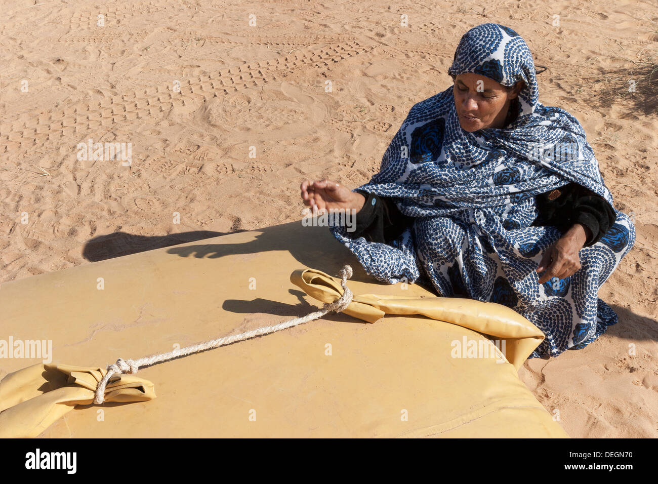 Femme de la famille nomade, portant le mulafa, robe traditionnelle mauritanienne, sur le point de prendre de l'eau dans la vessie de stockage dans la région de desert Banque D'Images