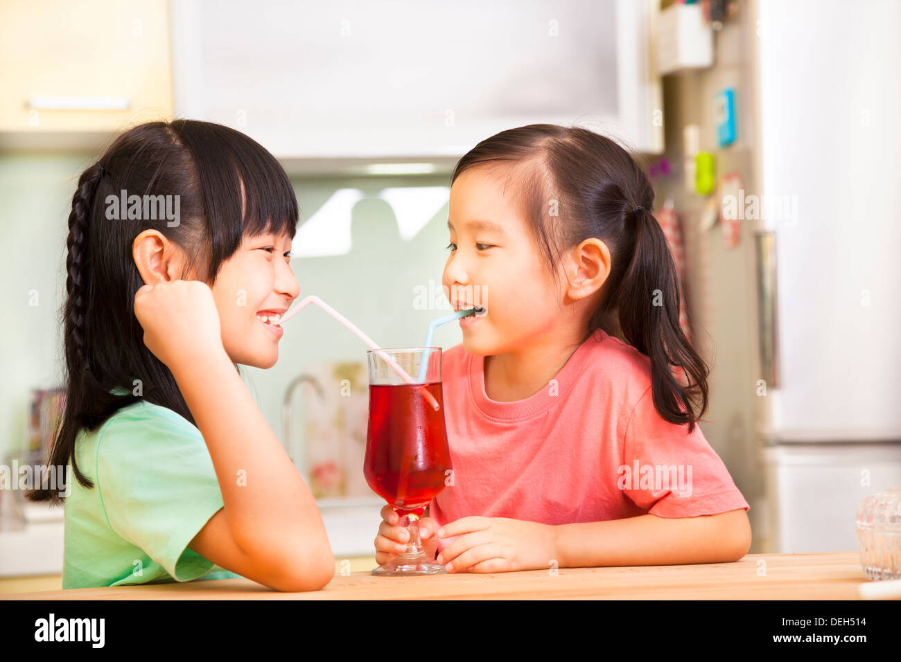 Deux petites filles boire du jus à la maison Banque D'Images