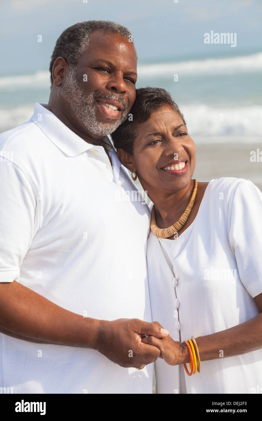 Happy senior African American man and woman couple holding hands sur une plage tropicale déserte Banque D'Images