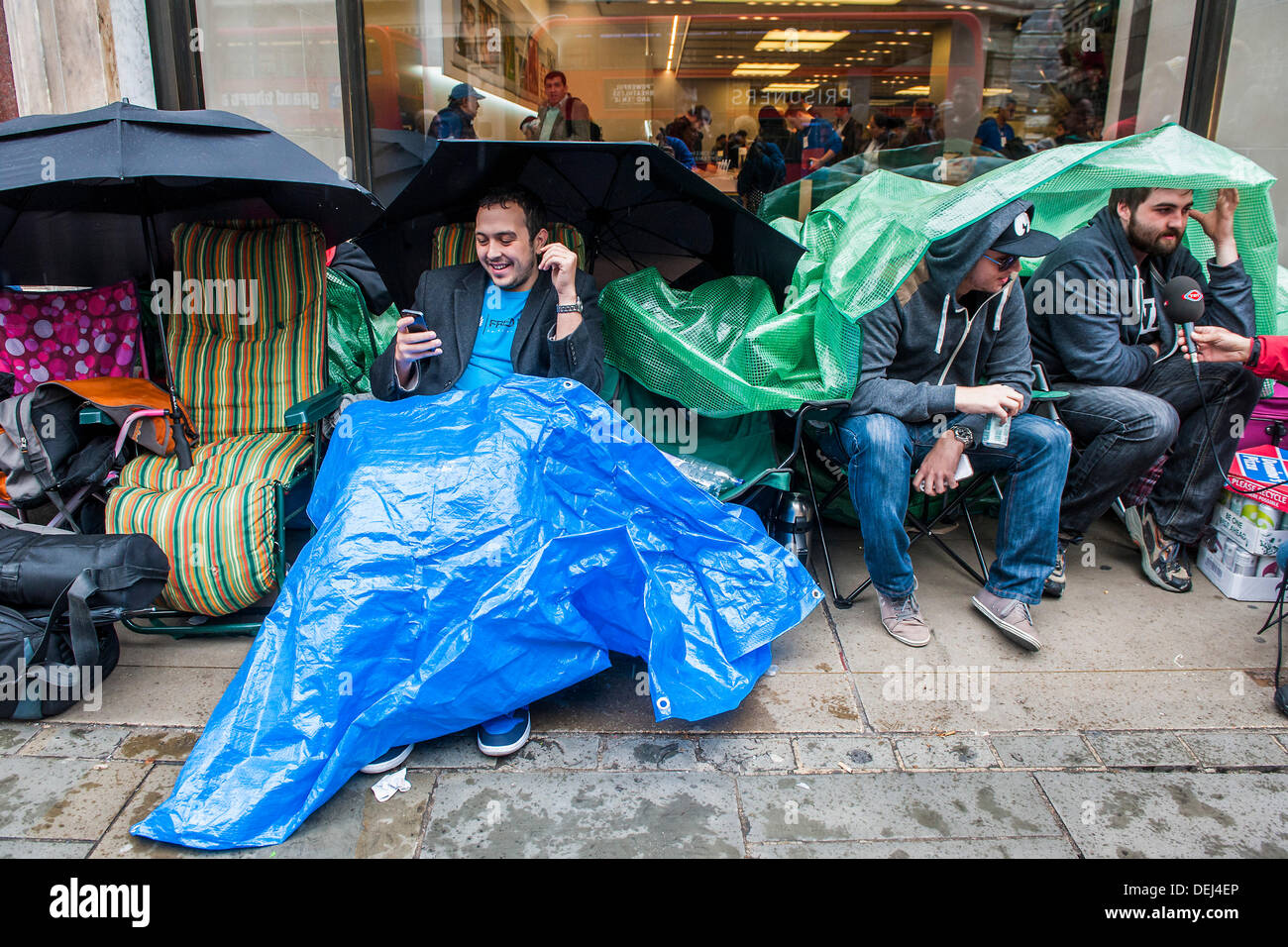 Londres, Royaume-Uni. 19e Août, 2013. La file d'attente pour le lancement de l'Apple i-phone 5 sous les parasols conciliabules dans la pluie. Il est constitué de ces personnes et d'une poignée dans le coin. Un lancement comme mauvais augure que le temps ? Mais, malgré l'apathie numérique le peu d'avoir manqué l'occasion de glaner des gratuités des vêtements et de la nourriture pour aider à rendre leur séjour 'payer'. La plupart ont également été organisés à l'argent pour sauver la place pour quelqu'un d'autre. peu permettrait de révéler s'ils avaient accepté. Bien que principalement plate il y a un flux constant de journalistes et des passants pour discuter avec. Crédit : Guy Bell/Alamy Live News Banque D'Images