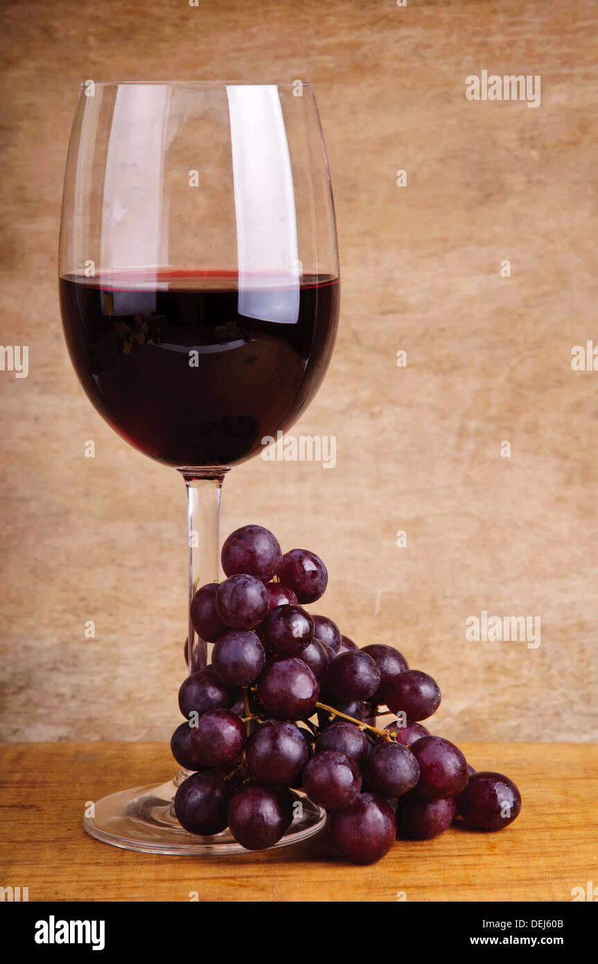 Verre de vin rouge et les raisins sur un fond de bois vintage Banque D'Images