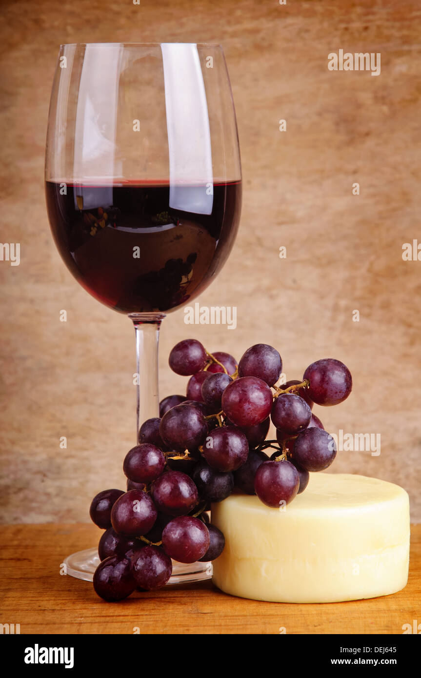 Nature morte au verre de vin rouge, les raisins et le fromage sur un arrière-plan vintage en bois Banque D'Images