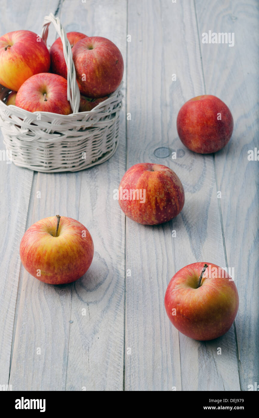 La vie encore. Panier blanc avec pommes rouges sur la table de bois blanc Banque D'Images