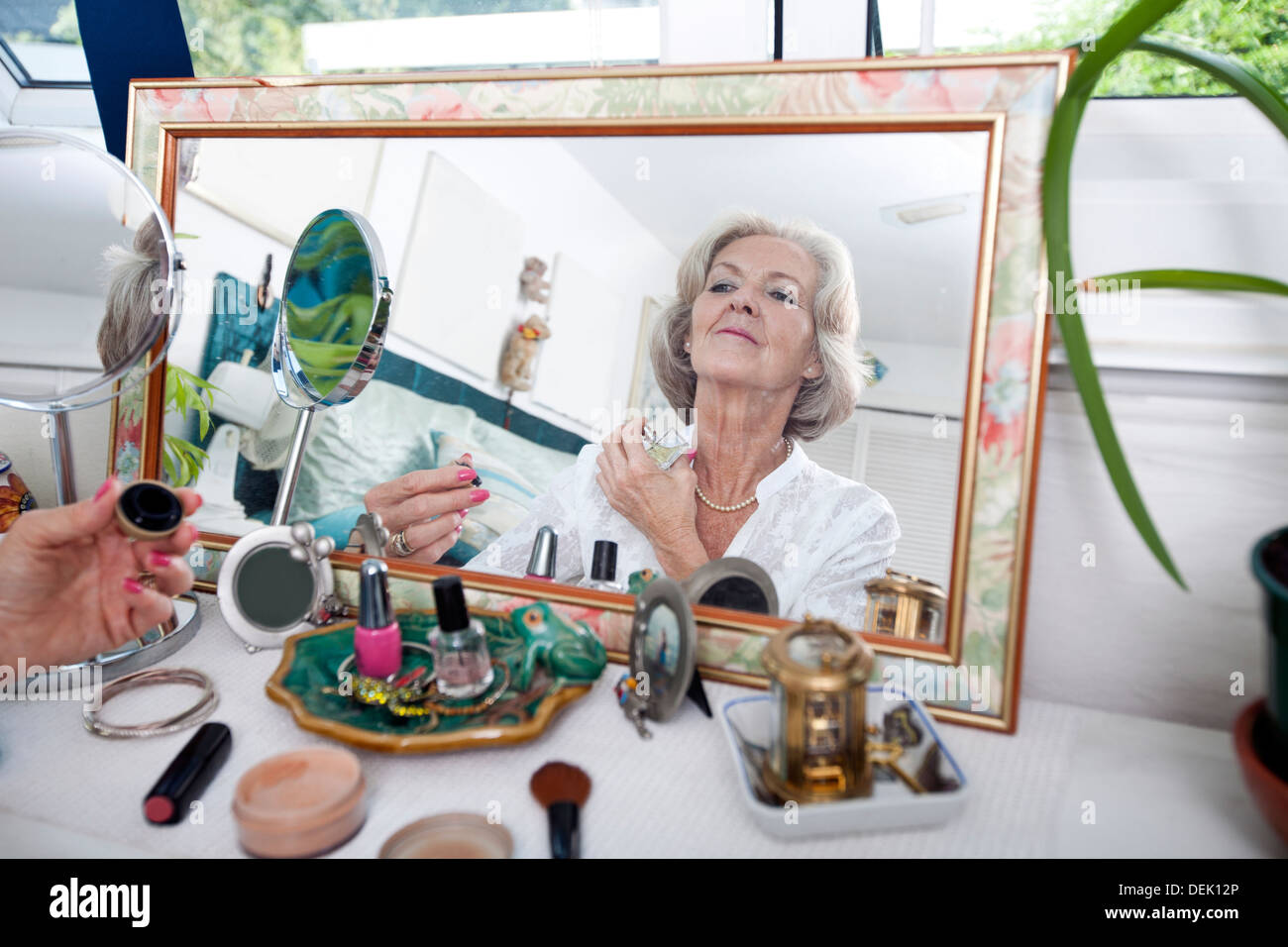 Reflet miroir senior woman spraying perfume sur elle-même accueil Banque D'Images