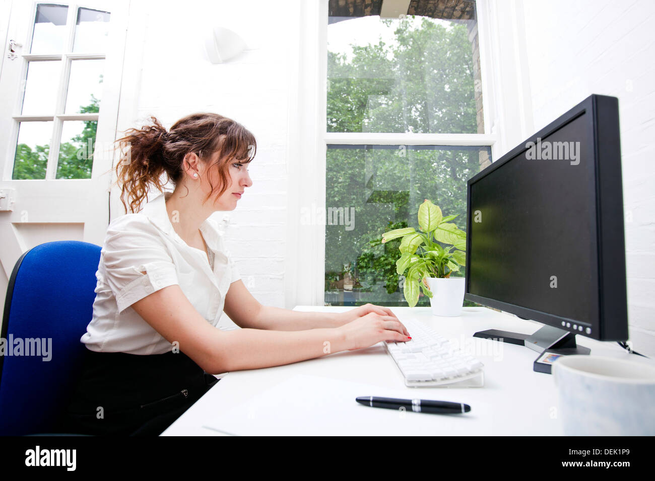 Vue latérale young businesswoman using computer desk Banque D'Images