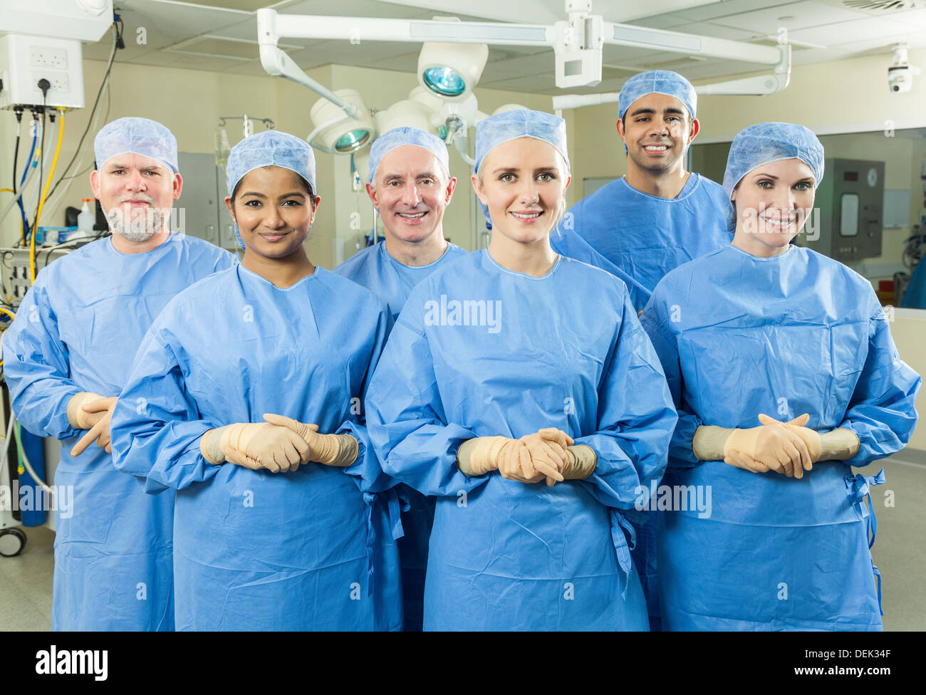 L'équipe médicale médecins chirurgiens interracial hommes femmes hôpital salle d'opération, le port de gants chirurgicaux gommages à heureux Banque D'Images