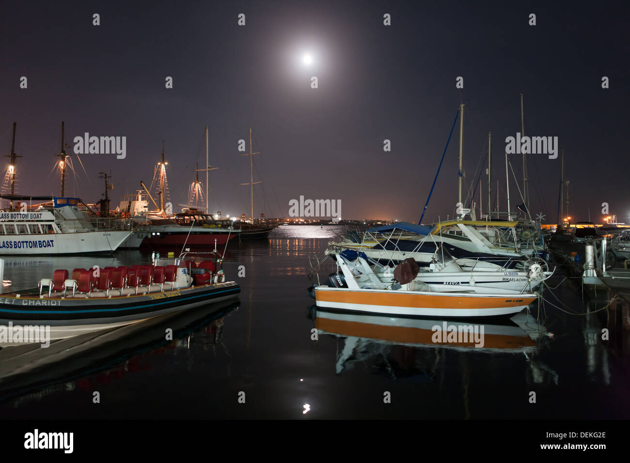 La pleine lune dans un ciel clair illumine le port en Yalikavak, Turquie. Des bateaux de plaisance se reposer après une journée de travail. Banque D'Images