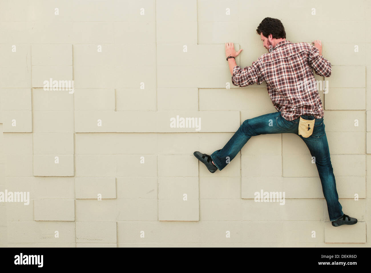 Caucasian climber scaling mur géométrique Banque D'Images