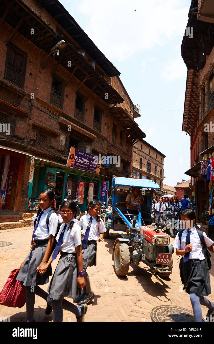 Le Népal Bhaktapur Ville (Khwopa ou Bhadgaon),groupe d'écoliers et de transports locaux communs -contre entre le tracteur et les tuk tuk. Banque D'Images