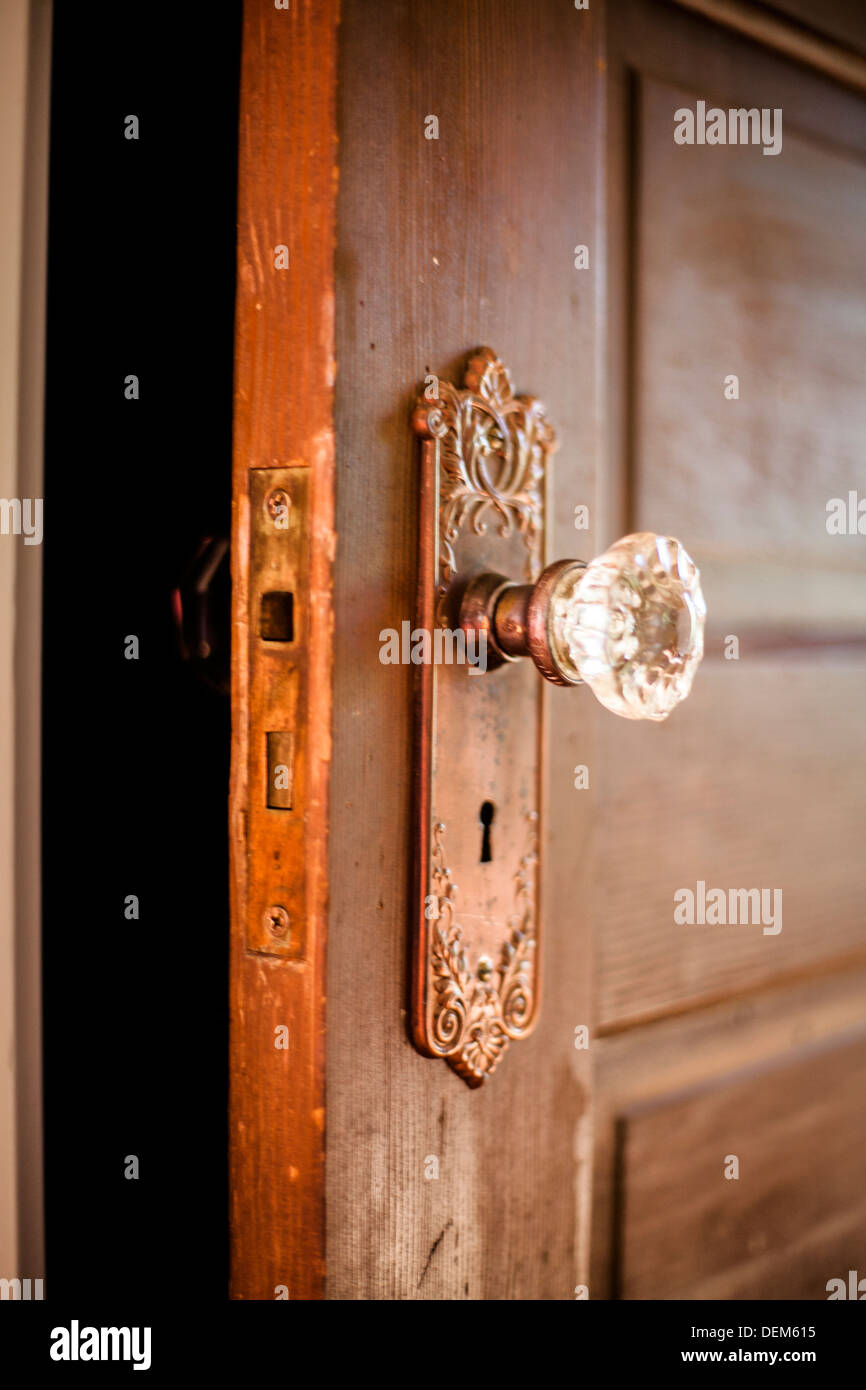 Libre d'une antique porte de bois à l'intérieur d'une maison avec une poignée de porte en verre et le skeleton key hole. Banque D'Images