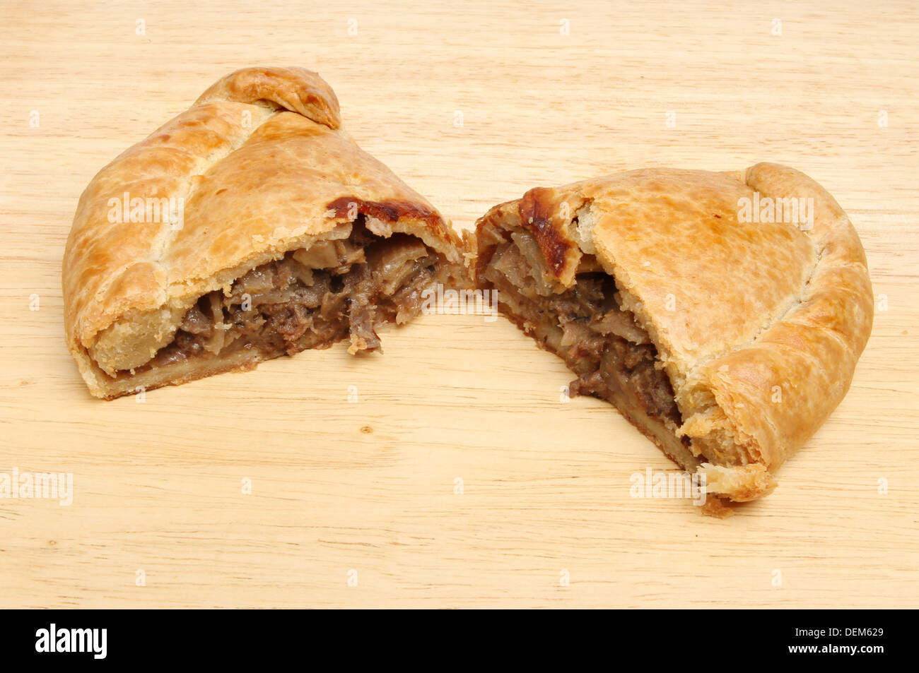 Cornish pasty coupé en deux moitiés sur une planche en bois Banque D'Images