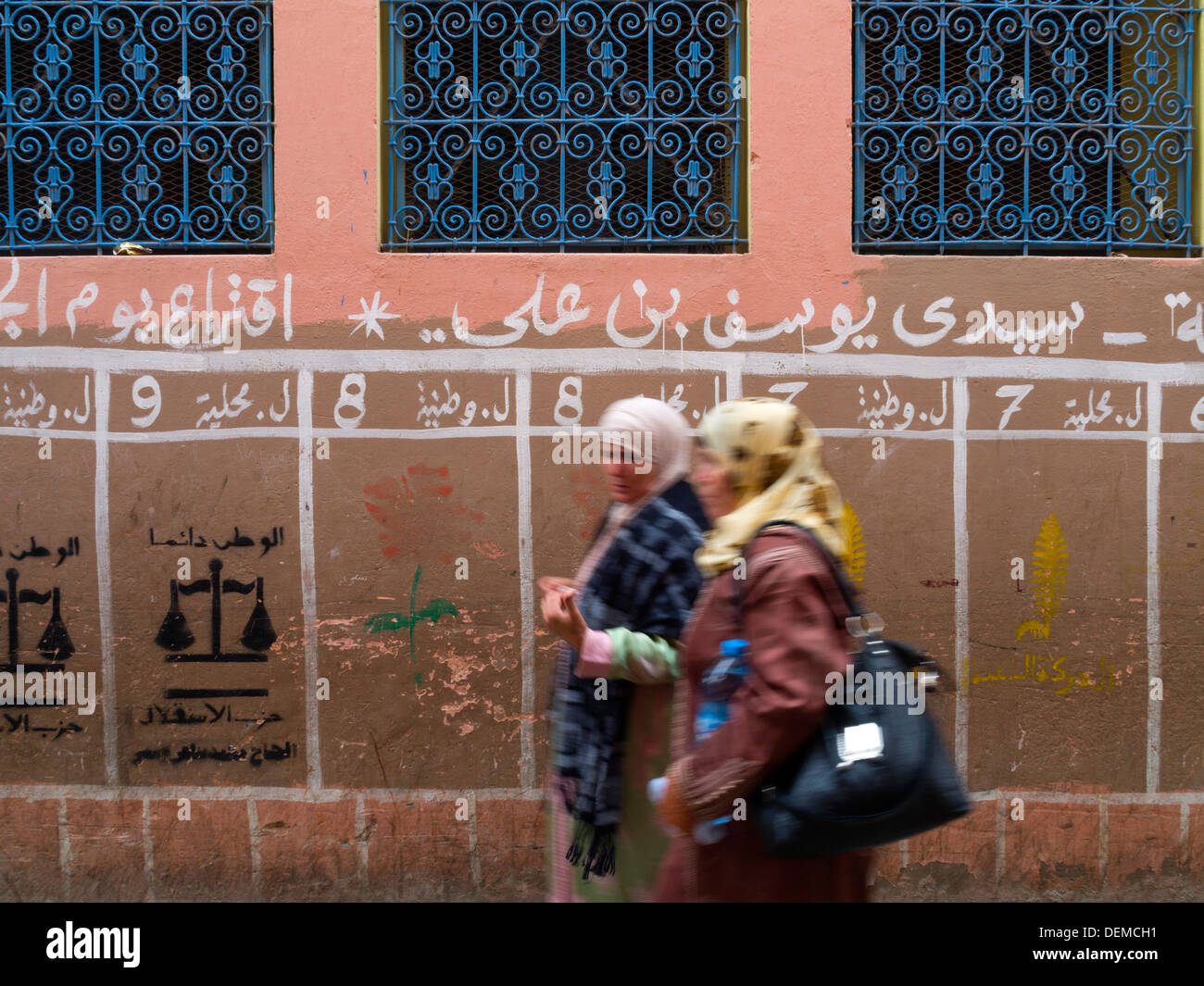 Motion blurred photo de deux femmes en passant en face de l'affiche électorale politique de réservation dans Marrakech, Maroc Banque D'Images