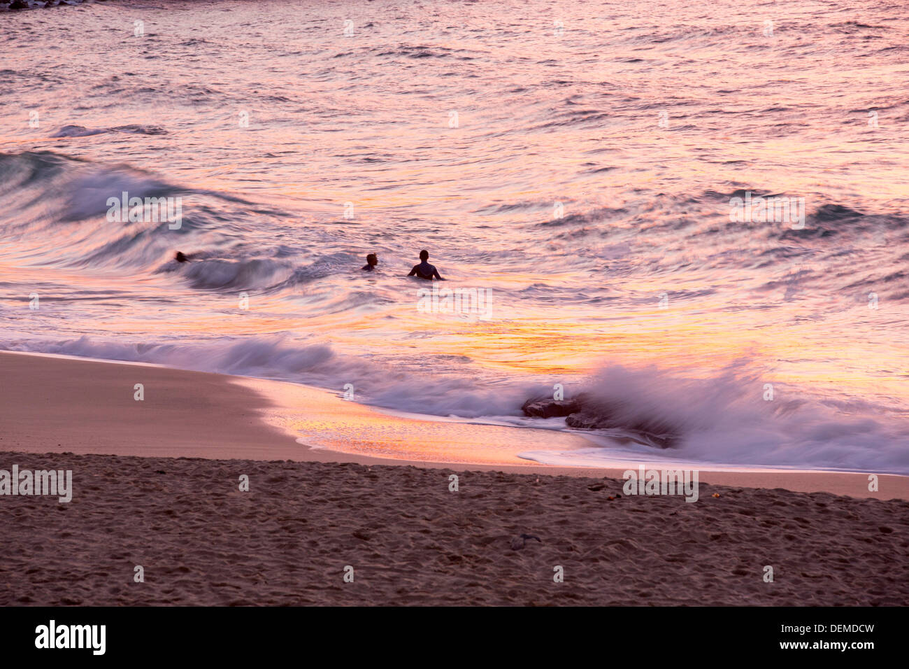 Les surfeurs sur la plage de Porthmeor à St Ives, Cornwall, UK, au coucher du soleil. Banque D'Images