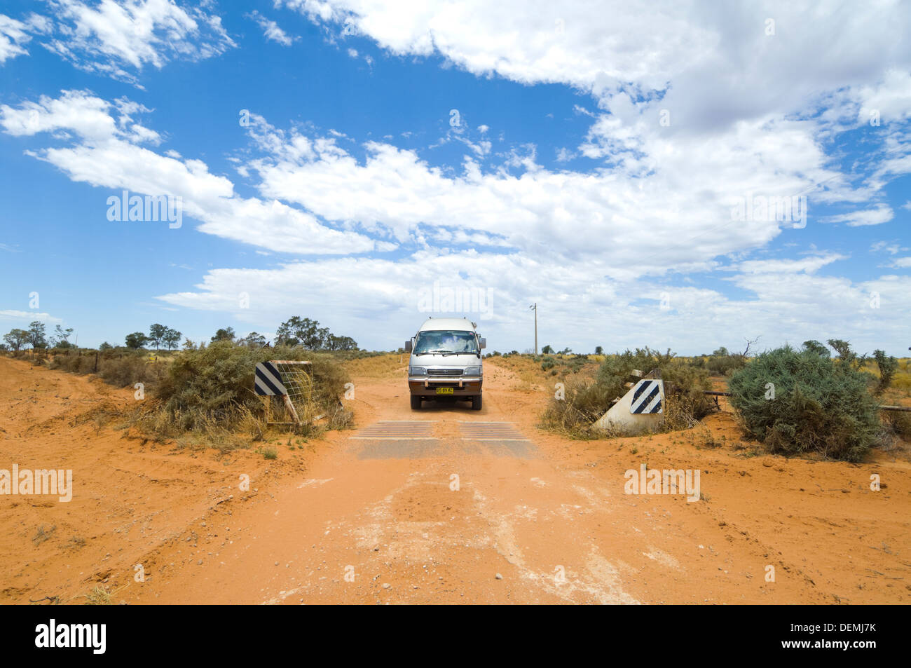 Aller sur une grille de bétail sur un chemin de terre dans une Toyota Hiace campervan, Mungo National Park, New South Wales, Australie Banque D'Images