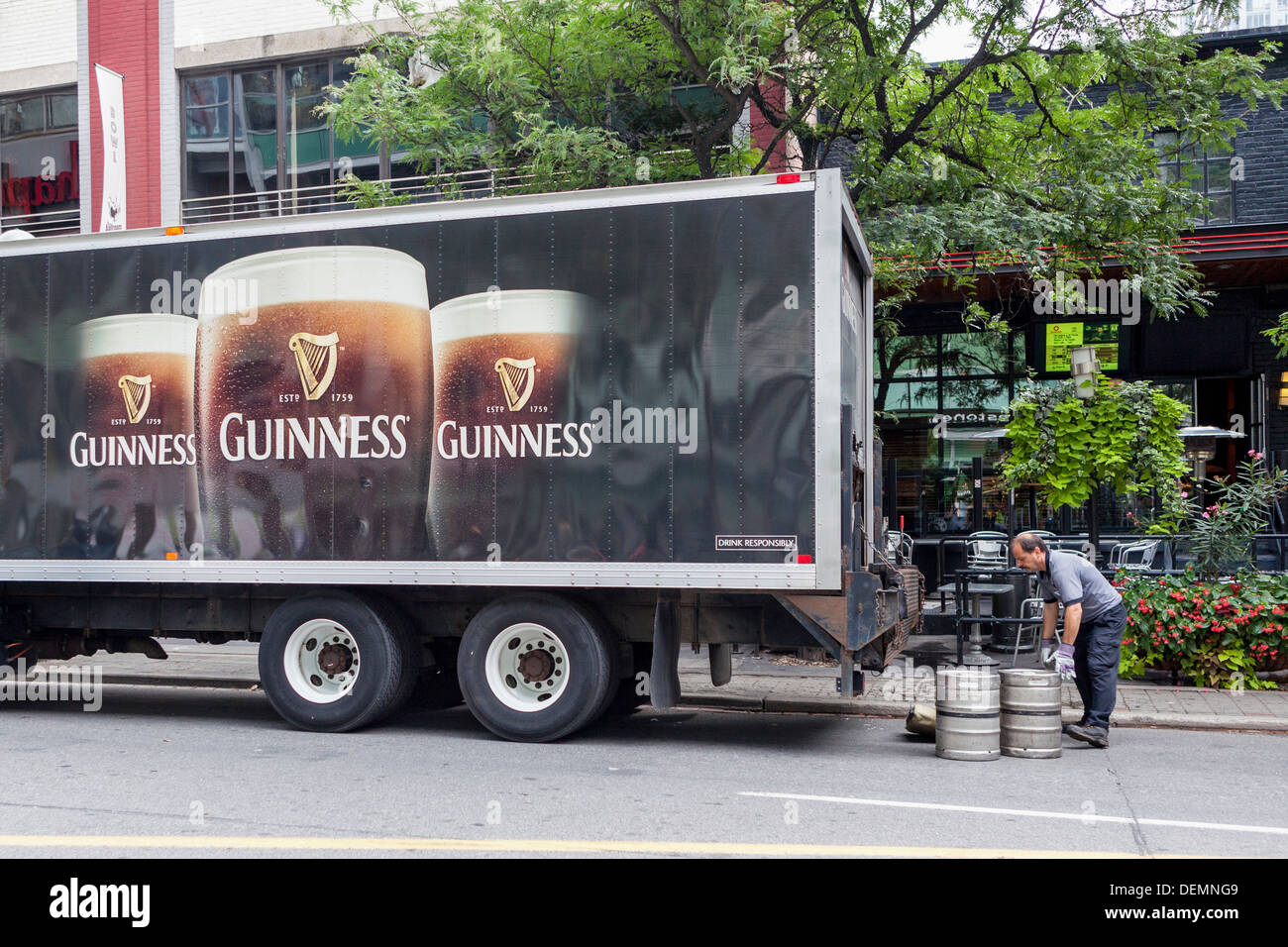 Homme installés tous les fûts d'bière Guinness un camion garé devant un bar de la rue John, Toronto Banque D'Images