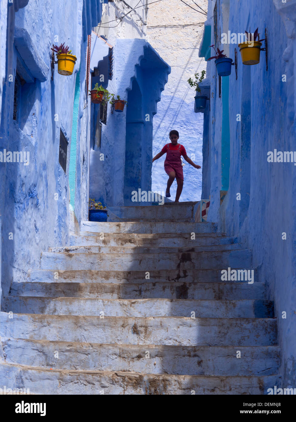 Jeune fille courir dans la rue avec des maisons peintes en bleu clair à Chefchaouen, Maroc Banque D'Images