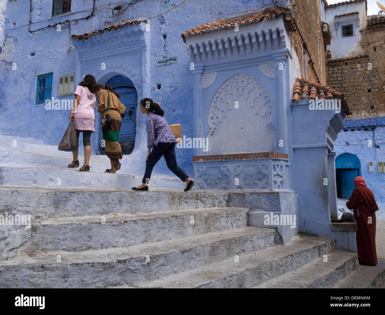 Trois enfants à pied vers le haut des escaliers à Chefchaouen, Maroc Banque D'Images