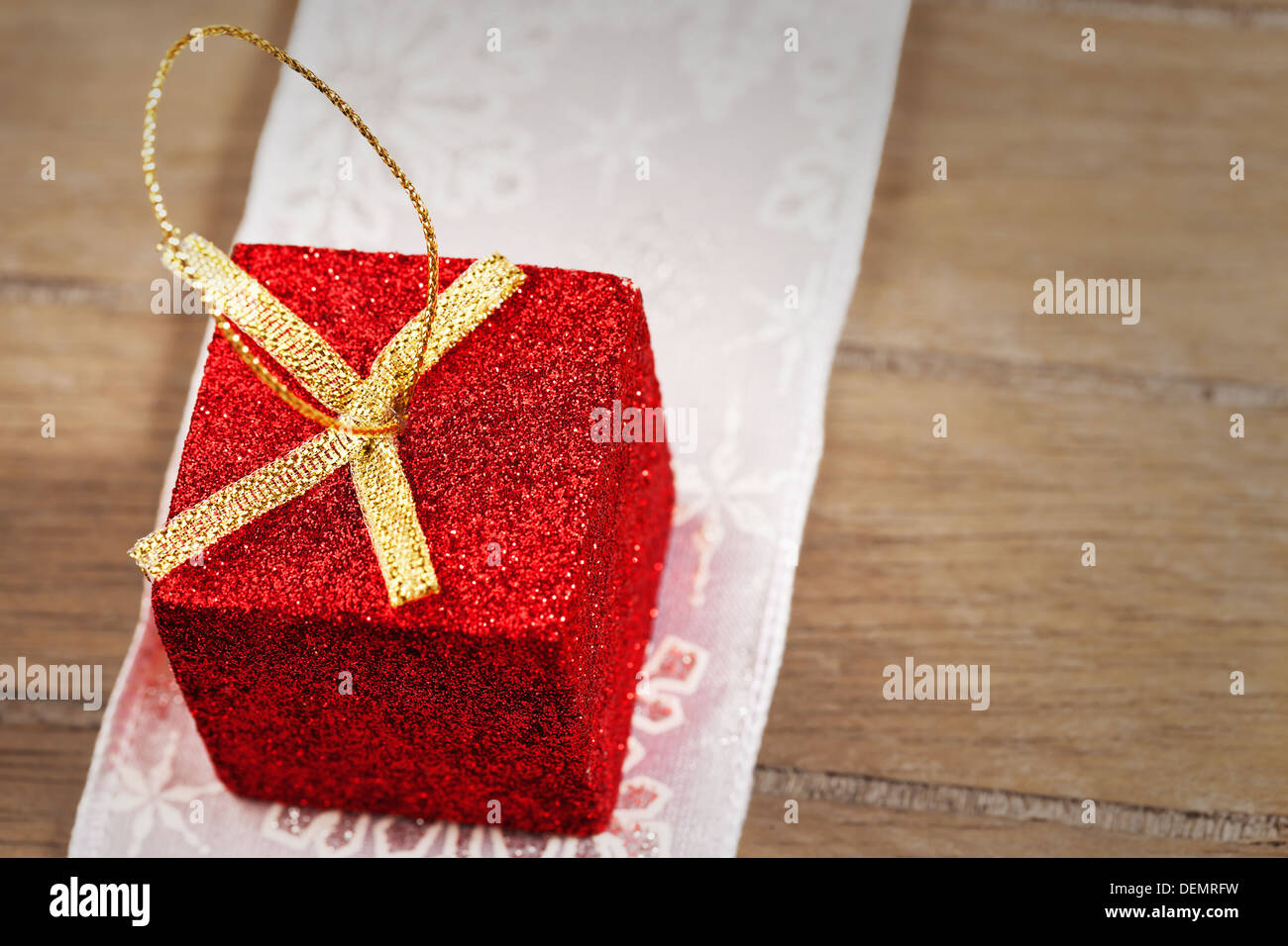 Libre d'un petit cadeau de noël paillettes rouge sur un ruban doré sur fond de bois Banque D'Images
