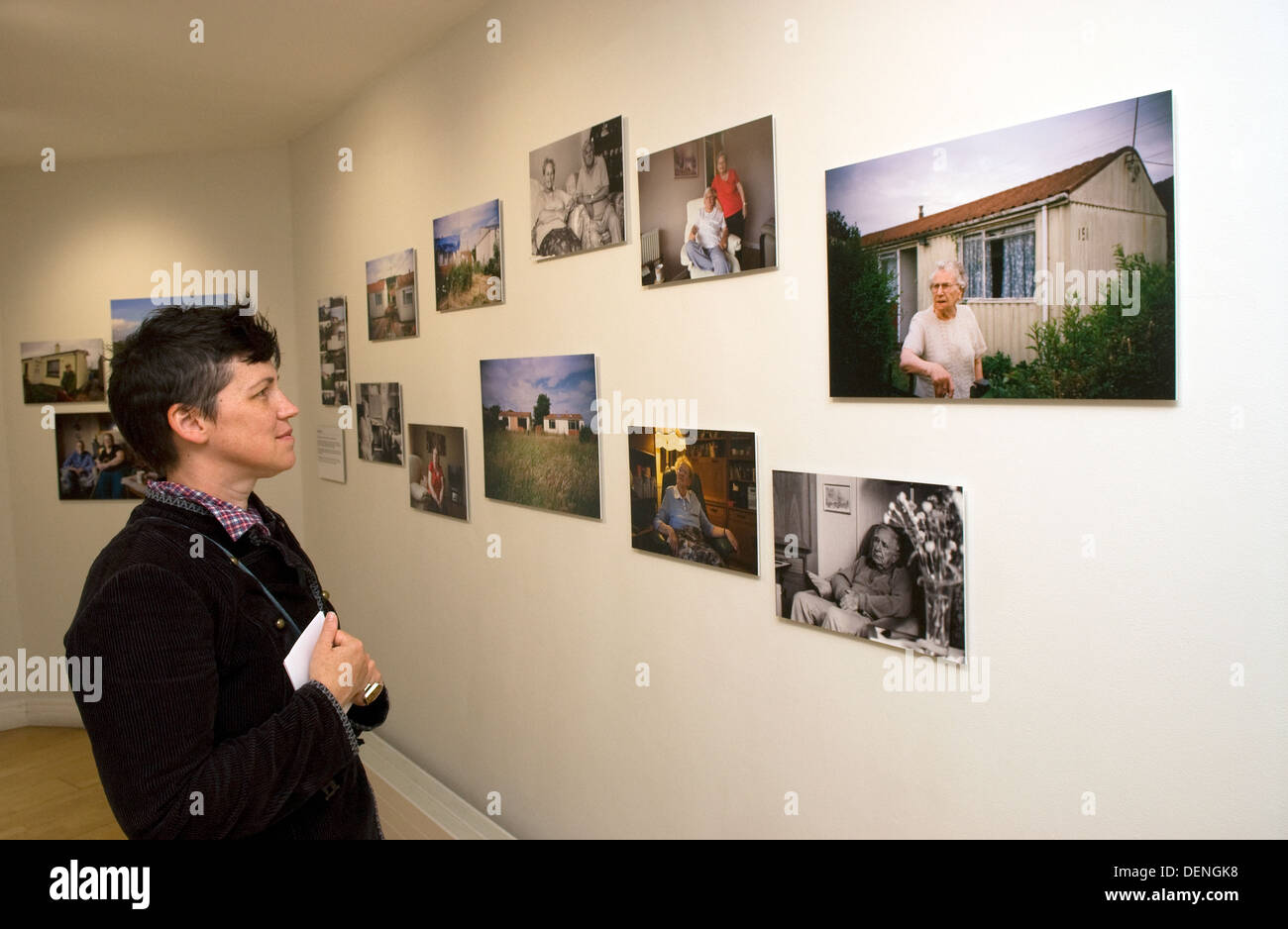 Femme feuilletant des photos sur un mur lors d'une exposition de la photographie documentaire à une galerie à Brixton, dans le sud de Londres, au Royaume-Uni. Banque D'Images
