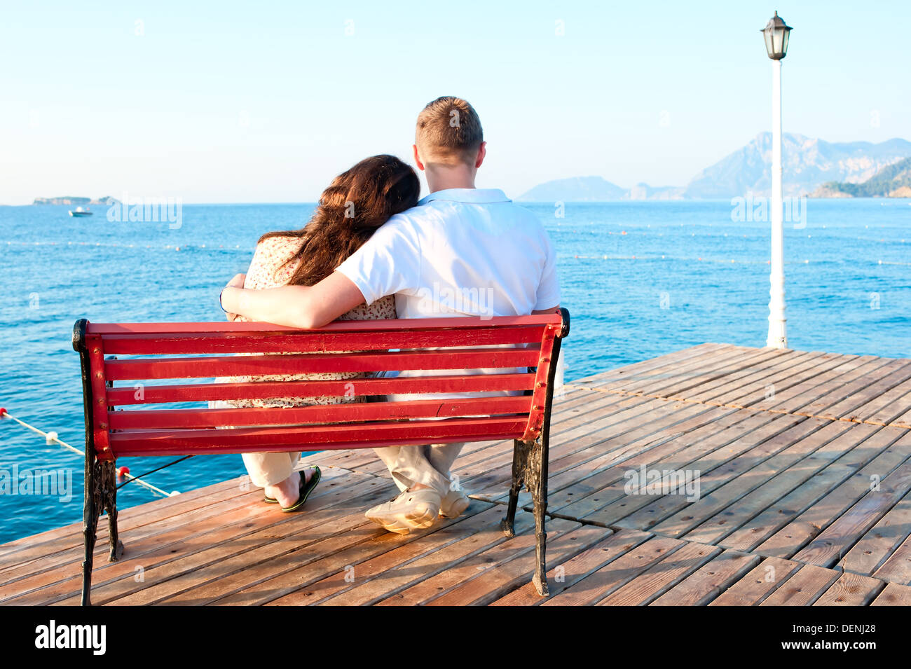Love couple assis sur un banc au bord de la mer embracing Banque D'Images