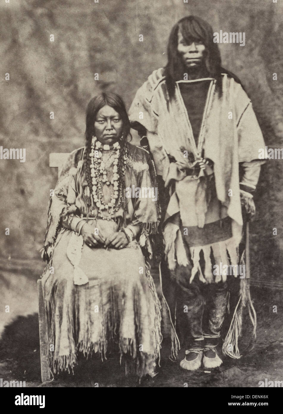 Kalispel couple, portrait en pied, l'homme debout, la femme assise, de face, portant des vêtements traditionnels, circa 1861 Banque D'Images