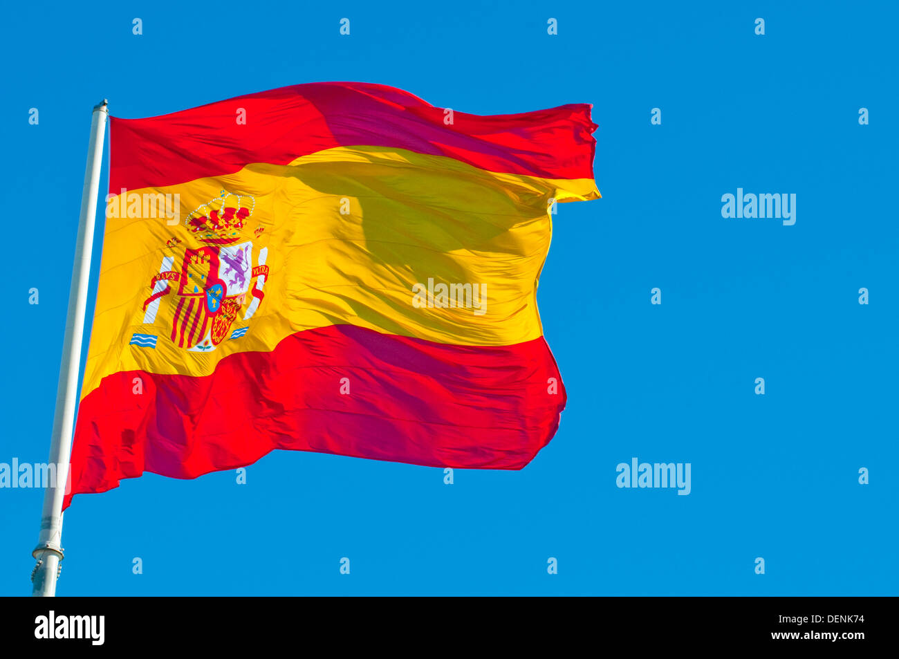 Brandir le drapeau espagnol sur fond de ciel bleu. Banque D'Images