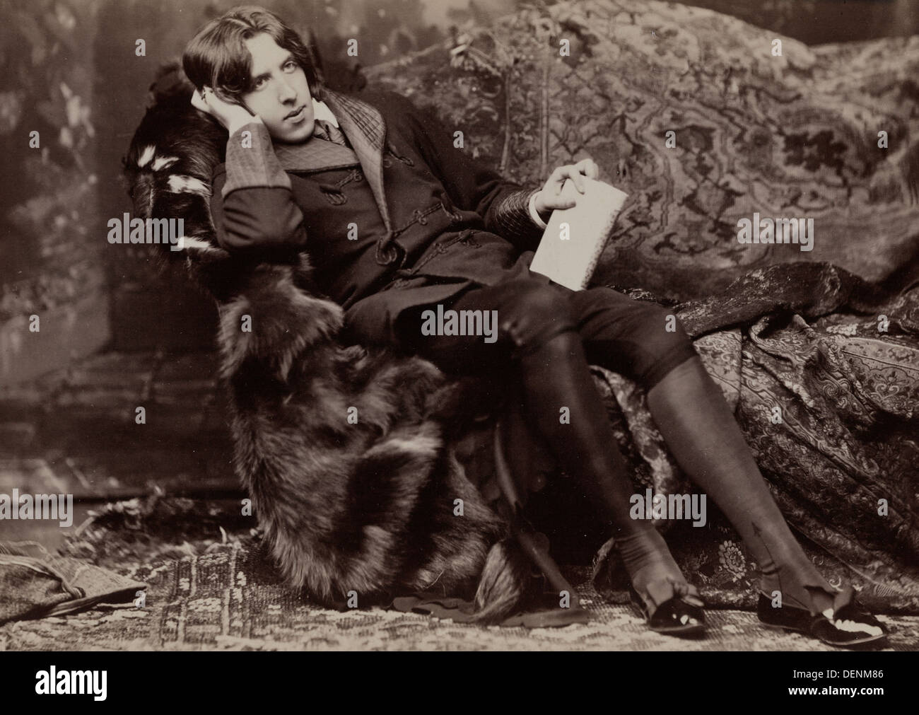 Oscar Wilde, portrait en pied, faisant face à droite, assis sur une chaise, la main droite sur la joue gauche, main tenant d'adresses. 1882 Banque D'Images