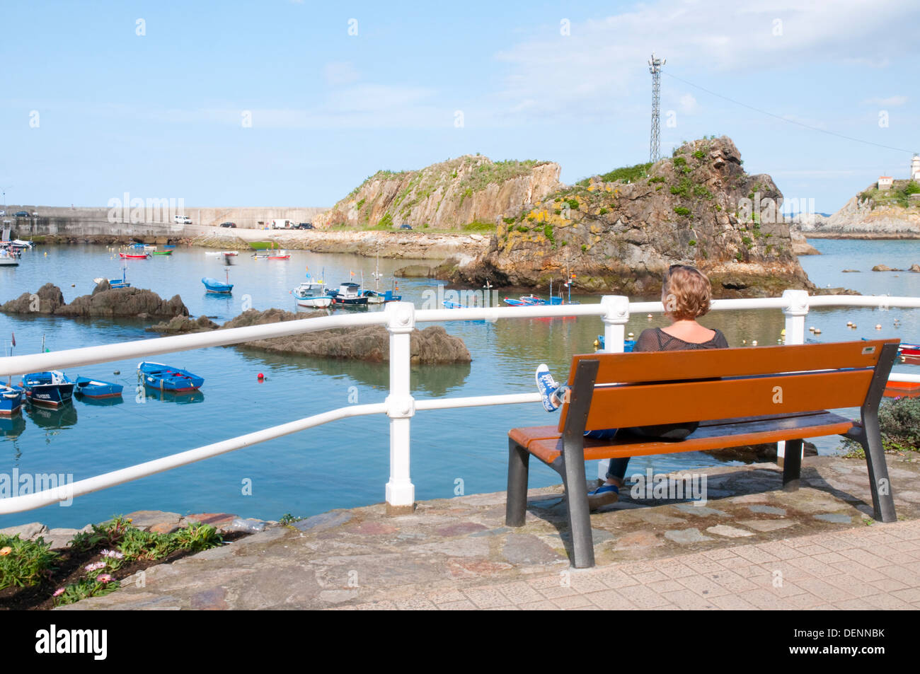 Femme assise sur un banc au port. Cudillero, Asturias, Espagne. Banque D'Images