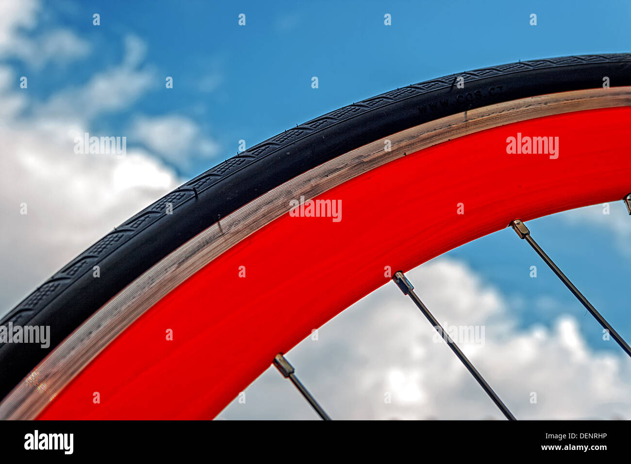 Détail d'une roue de vélo avec caoutchouc jante orange sur un fond de ciel. Banque D'Images