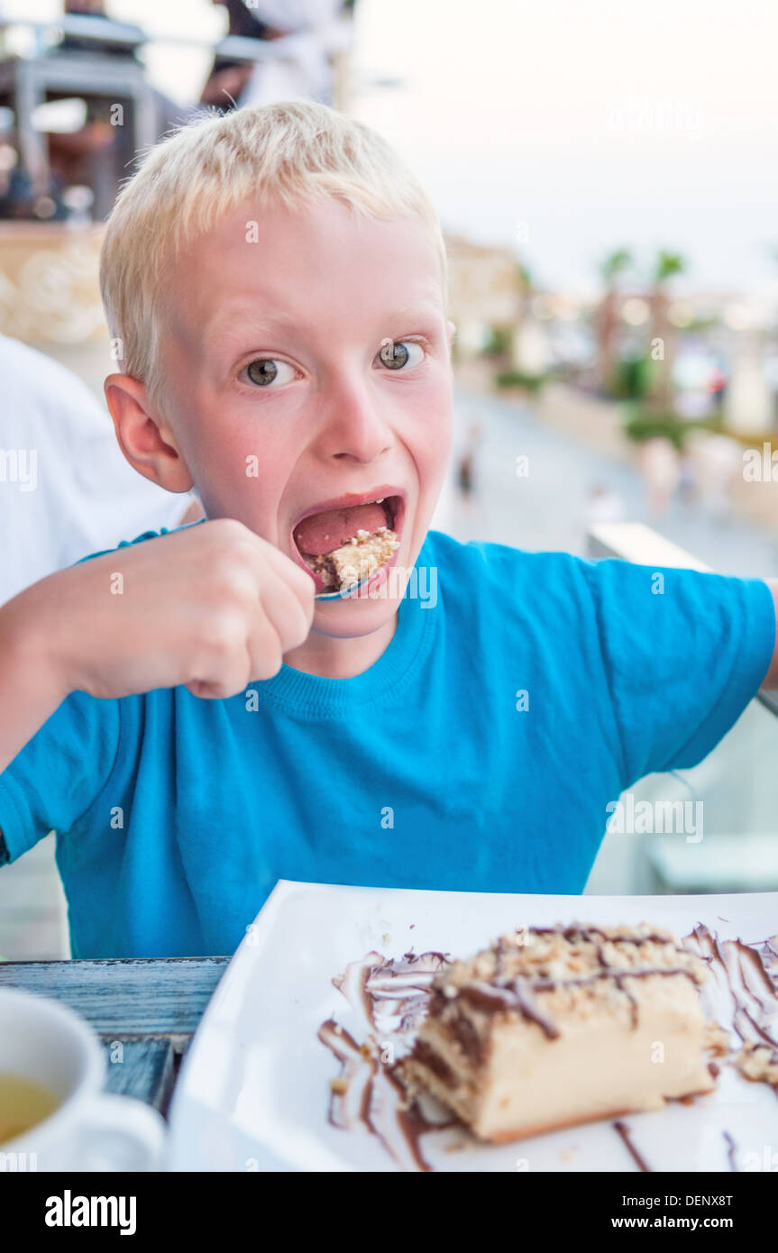 Jeune garçon de manger un gâteau à l'extérieur Banque D'Images