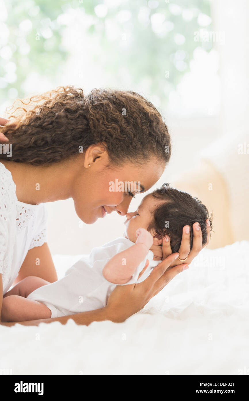 Hispanic mother holding infant on bed Banque D'Images