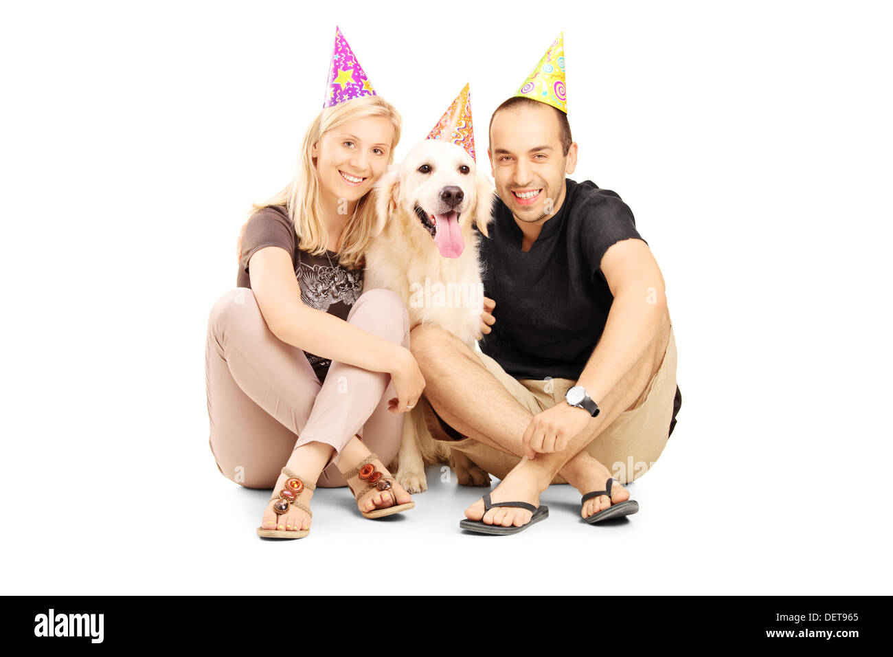 Couple hétérosexuel wearing party hats avec leur chien assis sur un marbre Banque D'Images