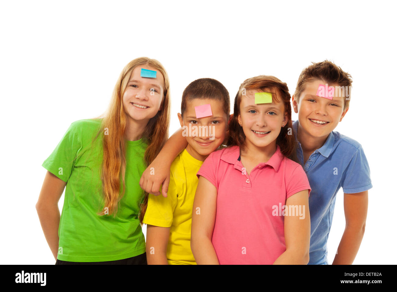 Quatre enfants smiling avec papier couleur autocollant sur eux Banque D'Images