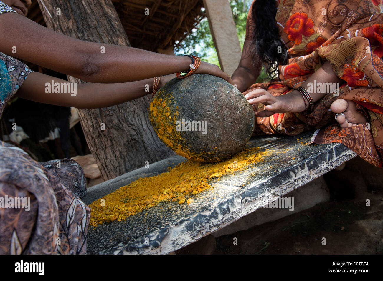 Deux femmes indiennes curcuma poudre de racines de broyage avec une pierre ronde dans un village de l'Inde rurale. L'Andhra Pradesh, Inde Banque D'Images